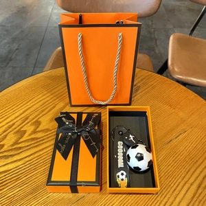 Detail of football keychain set with ball pendant and GOOOOAL strap in orange gift box