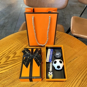 Soccer gift set featuring 3D football pendant and designer orange gift box on wood