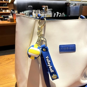 Detailed shot of a blue, yellow and white volleyball keychain on a white leather tote bag