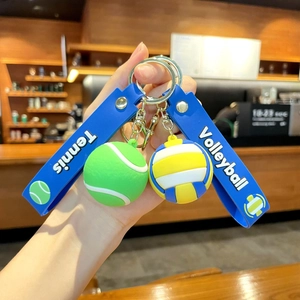 Close-up of sports keychains featuring a green tennis ball and yellow blue volleyball