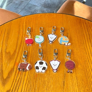 Vue détaillée de huit jolis porte-clés de sport en acrylique sur une table en bois ronde