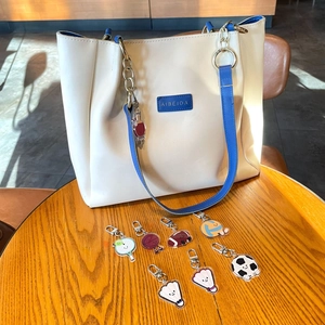Gros plan sur sac cabas blanc avec pendentifs sportifs colorés en acrylique