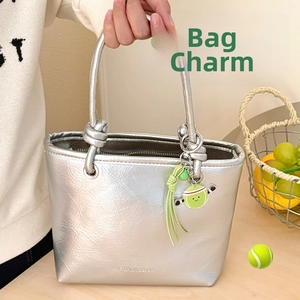 Détail d'un porte-clés tennis avec gland vert sur un sac à main en similicuir argenté