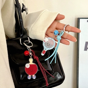 Détail de porte-clés en acrylique tennis et badminton suspendus à un sac noir élégant