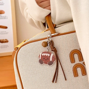 Détail d'un porte-clés football en acrylique avec pompon marron sur un sac à main
