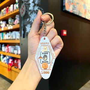 Close-up of retro hotel-style acrylic keychain with bread illustrations and handmade text