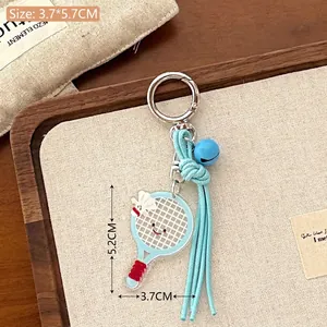Porte-clés raquette de badminton bleue avec volant et clochette sur plateau en bois