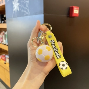 Détail d'un porte-clés de football 3D jaune et blanc avec bracelet assorti