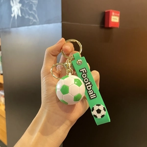 Détail d'un porte-clés football 3D avec dragonne en silicone verte et anneau doré