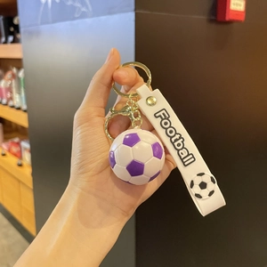 Détail d'un porte-clés de football violet et blanc avec anneau doré et lanière silicone