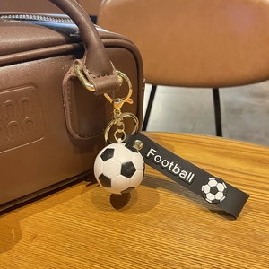 Porte-clés ballon de football noir et blanc avec anneau doré sur un sac en cuir brun