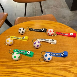 Lot de six porte-clés football colorés avec dragonne présentés sur une table en bois