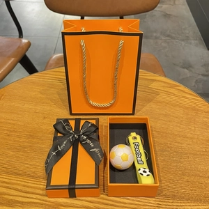 Détail d'un coffret cadeau porte-clés de football avec boîte orange et ruban élégant
