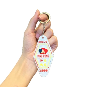 Pearlescent white acrylic Ping Pong hotel-style keychain held in hand on white background