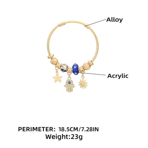 Detail of bohemian gold charm bracelet with Hamsa, sun, and stars charms on white background