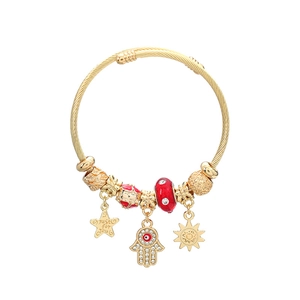 Bohemian gold twisted cable bracelet with Hamsa hand and sun charms on white background