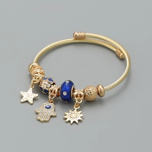 Detail of a gold-toned bangle with Hamsa Hand charm and 'Just for You' engraved star