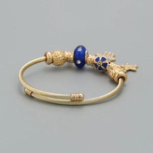 Detail of bohemian gold wire bracelet with blue enamel beads and star palm charms