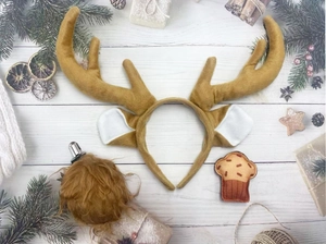 Detailed view of plush reindeer antler headband with festive ornaments on wood background