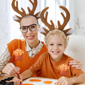Close-up of plush reindeer antler headband worn by adult and child in warm holiday setting
