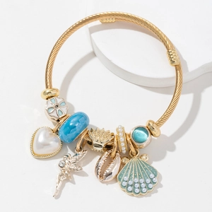 Gold twist rope bracelet featuring pearl heart, shell, and fairy charms with blue beads