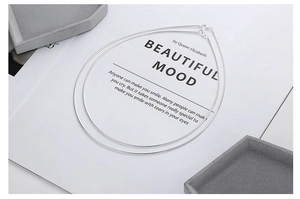 Detail of minimalist S925 sterling silver snake bone chains on a white book and stone tray