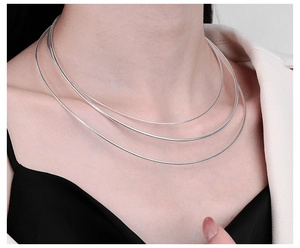 Three-layer silver snake chain necklace on model neck with minimalist jewelry style