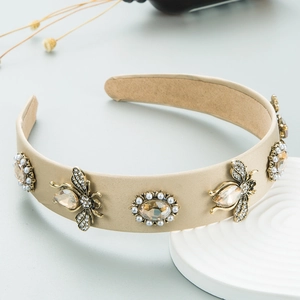 Detail of beige satin headband featuring crystal bees and pearl oval gemstone charms