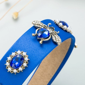 Detail of royal blue satin headband featuring a jeweled bee and pearl-set crystal