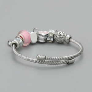 Detail of silver spiral wire bracelet with pink glass beads and heart charm