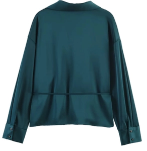 Detail view of the back of a dark green satin blouse with a waist tie and glossy texture
