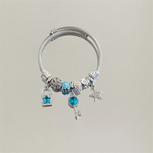 Detail of silver cable bracelet with blue star lock and jeweled key charms