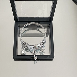 Macro detail of silver charm bracelet with key and star pendants in a black jewelry box