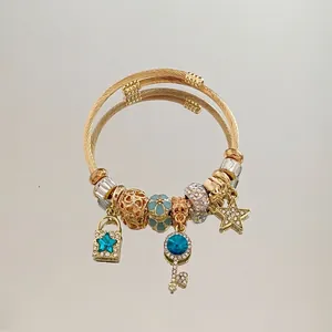 Macro shot of gold charm bracelet with blue star lock and key charms on a mirror