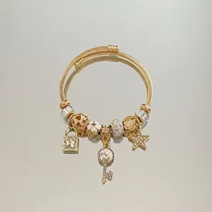 Detailed macro view of gold-plated star and key charms on a spiral textured bracelet