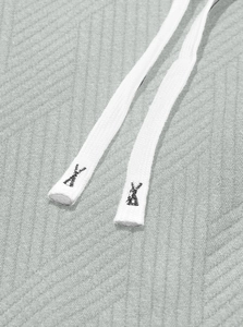 Detailed view of grey jacquard knit fabric and white woven drawstring with embroidery