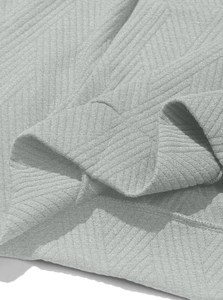 Detail of grey knitted fabric texture showing diagonal twill weave and stitching