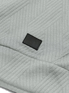 Detail of grey jacquard knit fabric featuring a textured pattern and black leather patch
