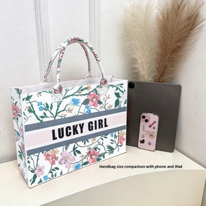 Detail of blue floral felt tote bag showing large capacity with tablet and phone for scale