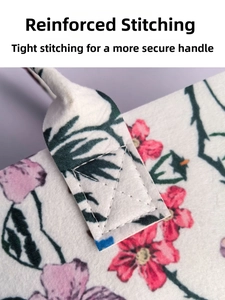 Close-up of reinforced X-shaped cross-stitching on the floral felt tote bag handle