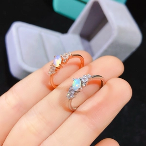 Close-up of rose gold and silver opal rings with vibrant fire on a model's finger
