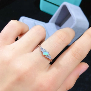 Close-up of natural oval opal ring with side diamonds on hand against gift box
