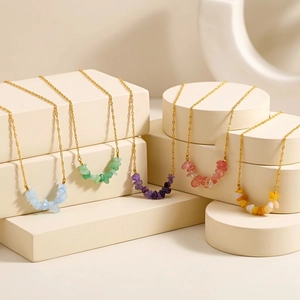 Detail of five assorted natural stone chip necklaces on elegant cream display stands