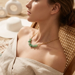 Bohemian gold chain necklace with natural green raw stones worn by a model on a beach