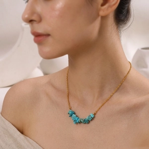 Close-up of a gold necklace with irregular turquoise stones worn by a model