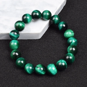Macro shot of 8mm dark green tiger eye beaded bracelet with cat eye effect on marble stone