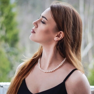 Elegant single strand white pearl necklace worn by a model in a natural light setting
