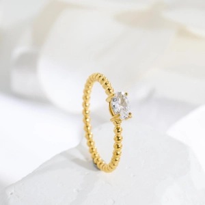 Close-up of oval zircon 18K gold ring with bubble textured band on white stone