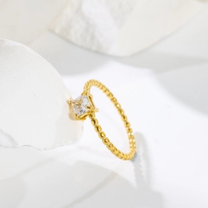 Detailed view of square zircon 18K gold plated ring with beaded band on white rock