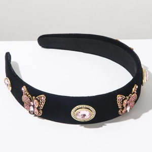 Detailed view of black velvet headband featuring golden metal butterflies and pink gems